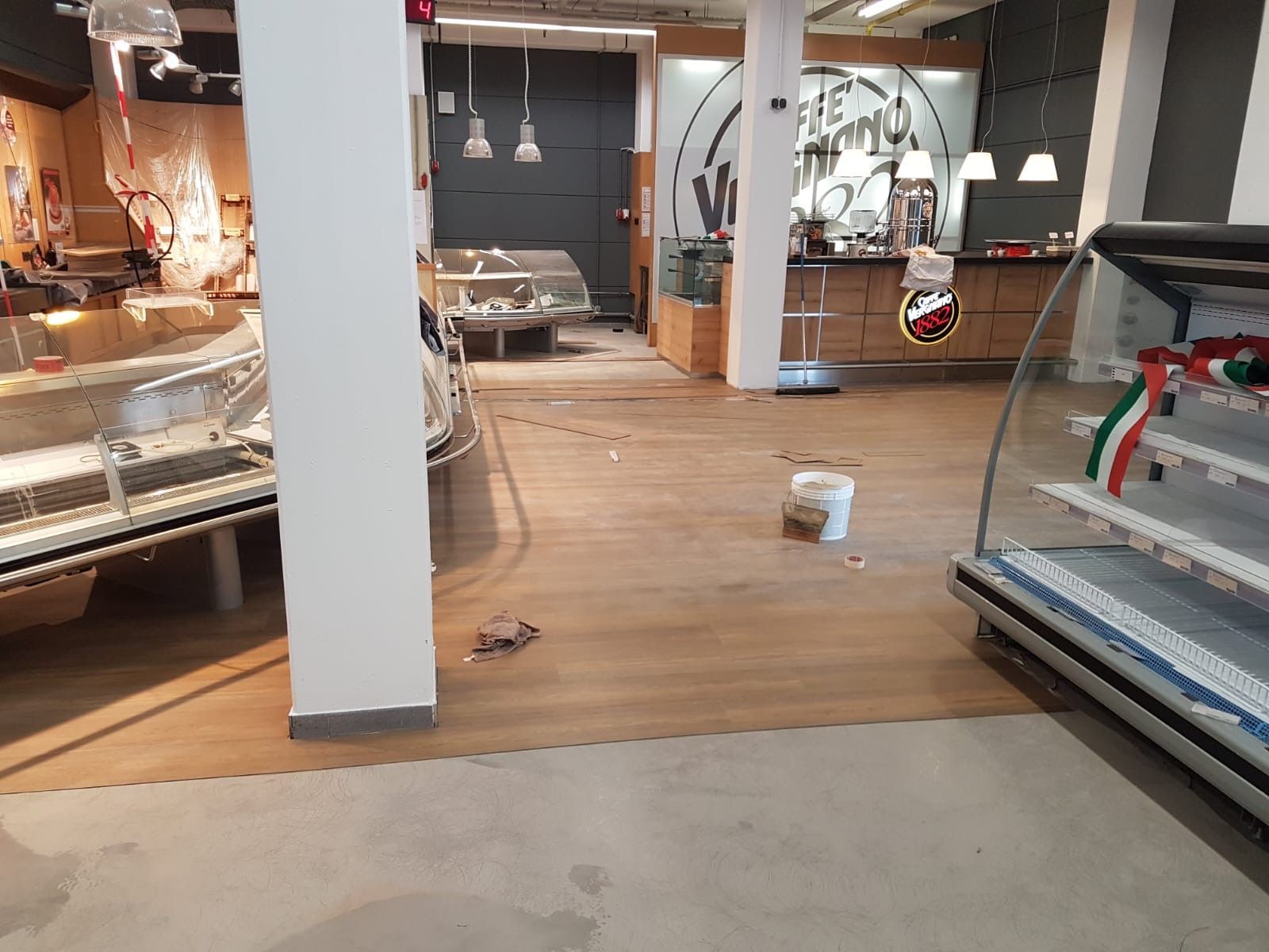 Leerer Ladeninnenraum mit Vitrinen, Holzboden und einer weißen Säule.