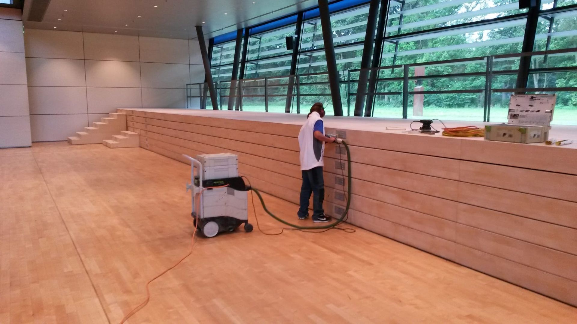 Eine Person saugt einen Holzboden in einem großen, modernen Gebäude.