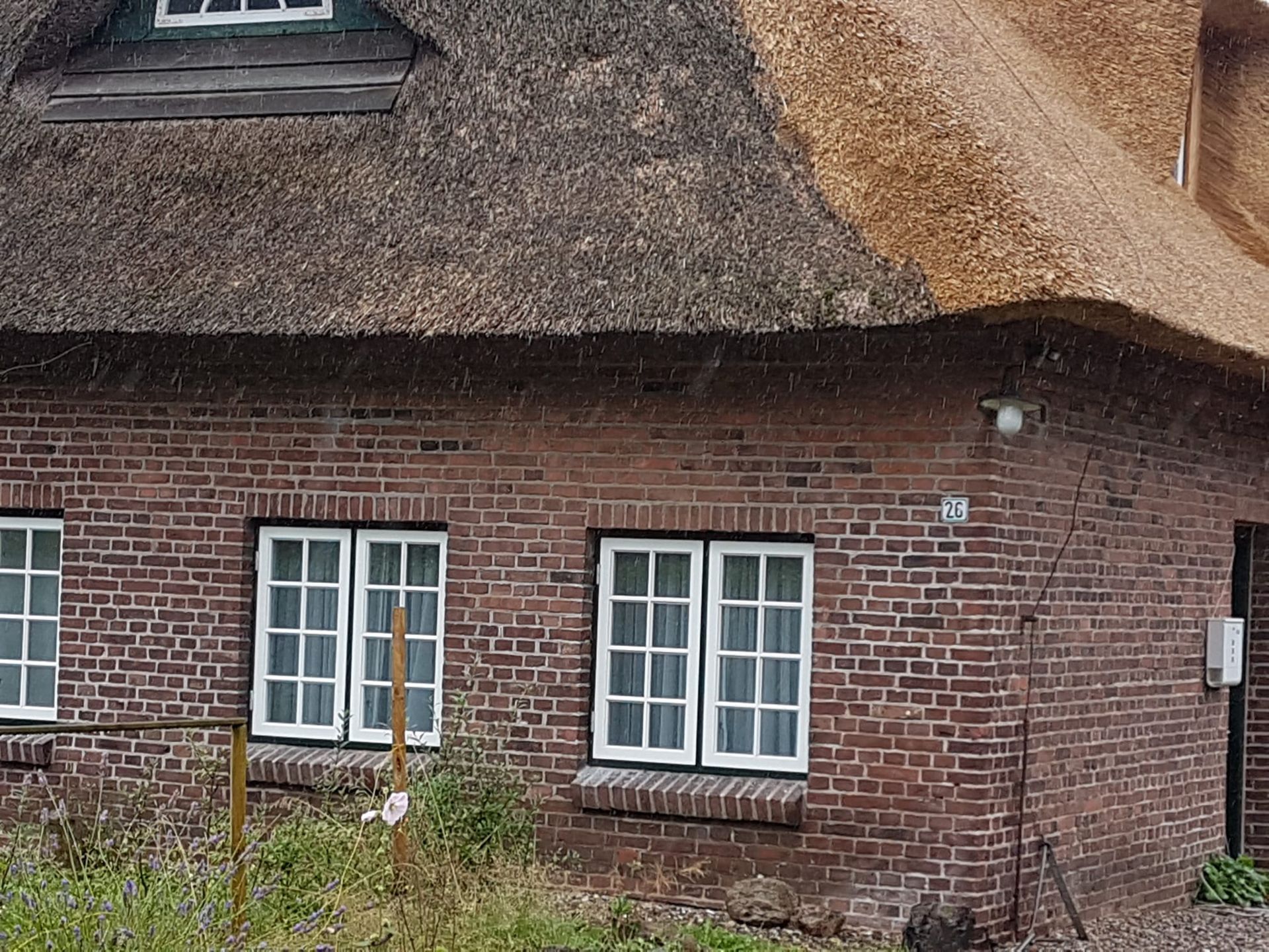 Ein Backsteinhaus mit Strohdach und weißen Fenstern