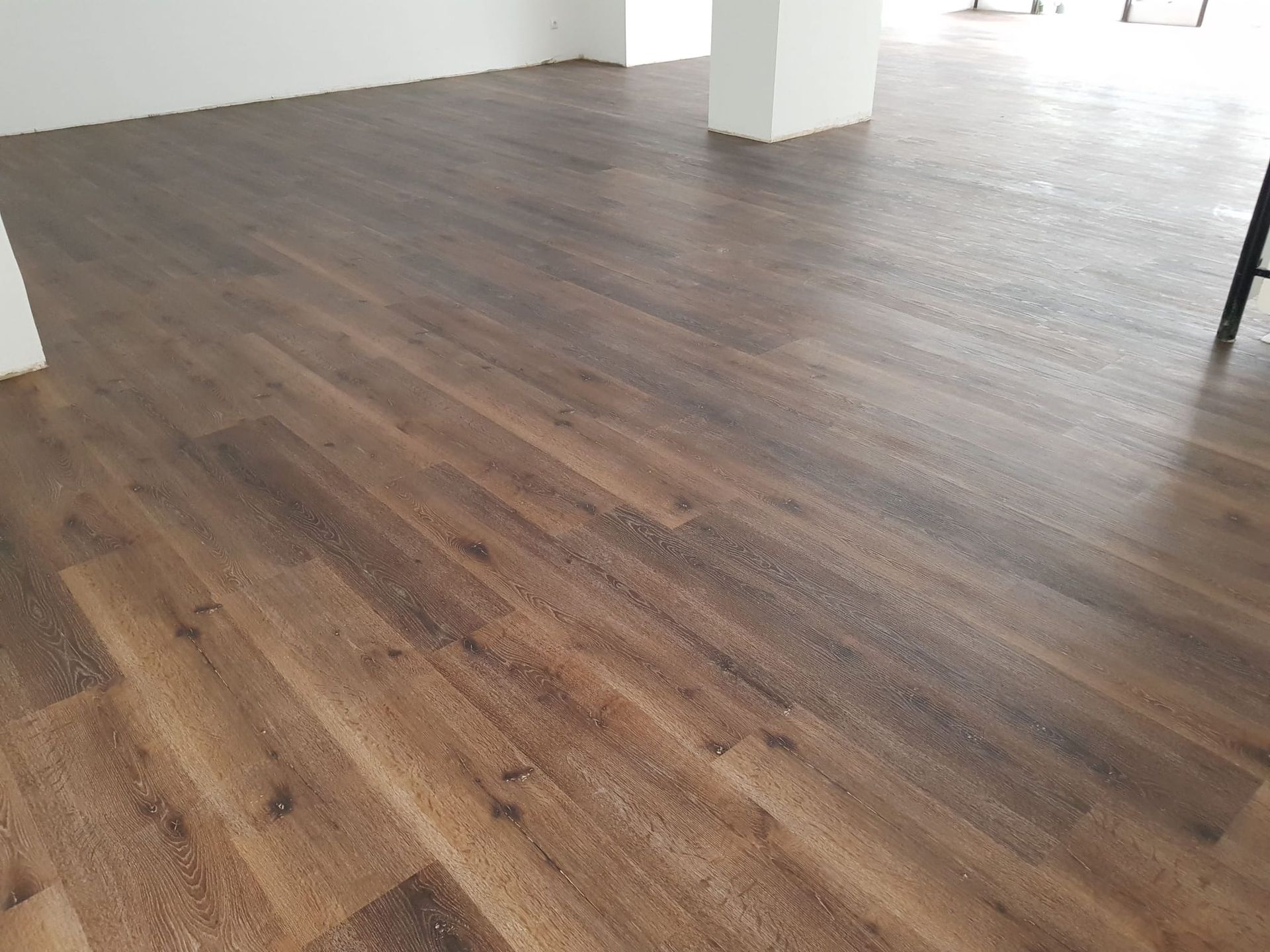 Holzboden mit braunen Dielen in einem Raum mit weißen Wänden.