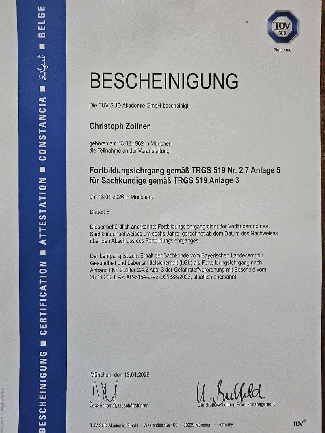 Deutsches Zertifikat mit Text, „BESCHEINIGUNG“ und TÜV-Logo. Enthält Text und Unterschriften.