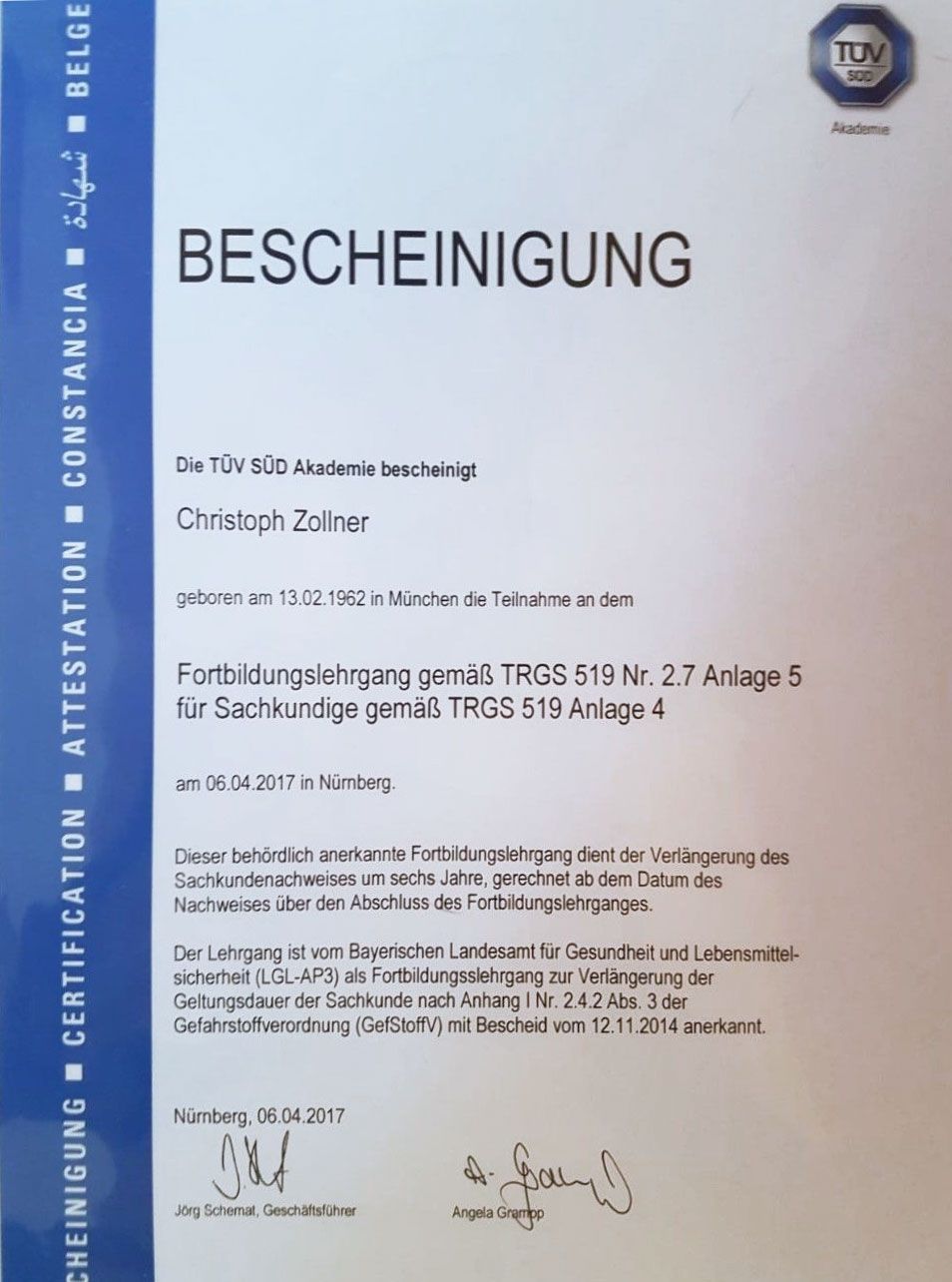 Zertifikat mit deutschem Text. „BESCHEINIGUNG“ ist sichtbar. Oben rechts ein TÜV-Logo.