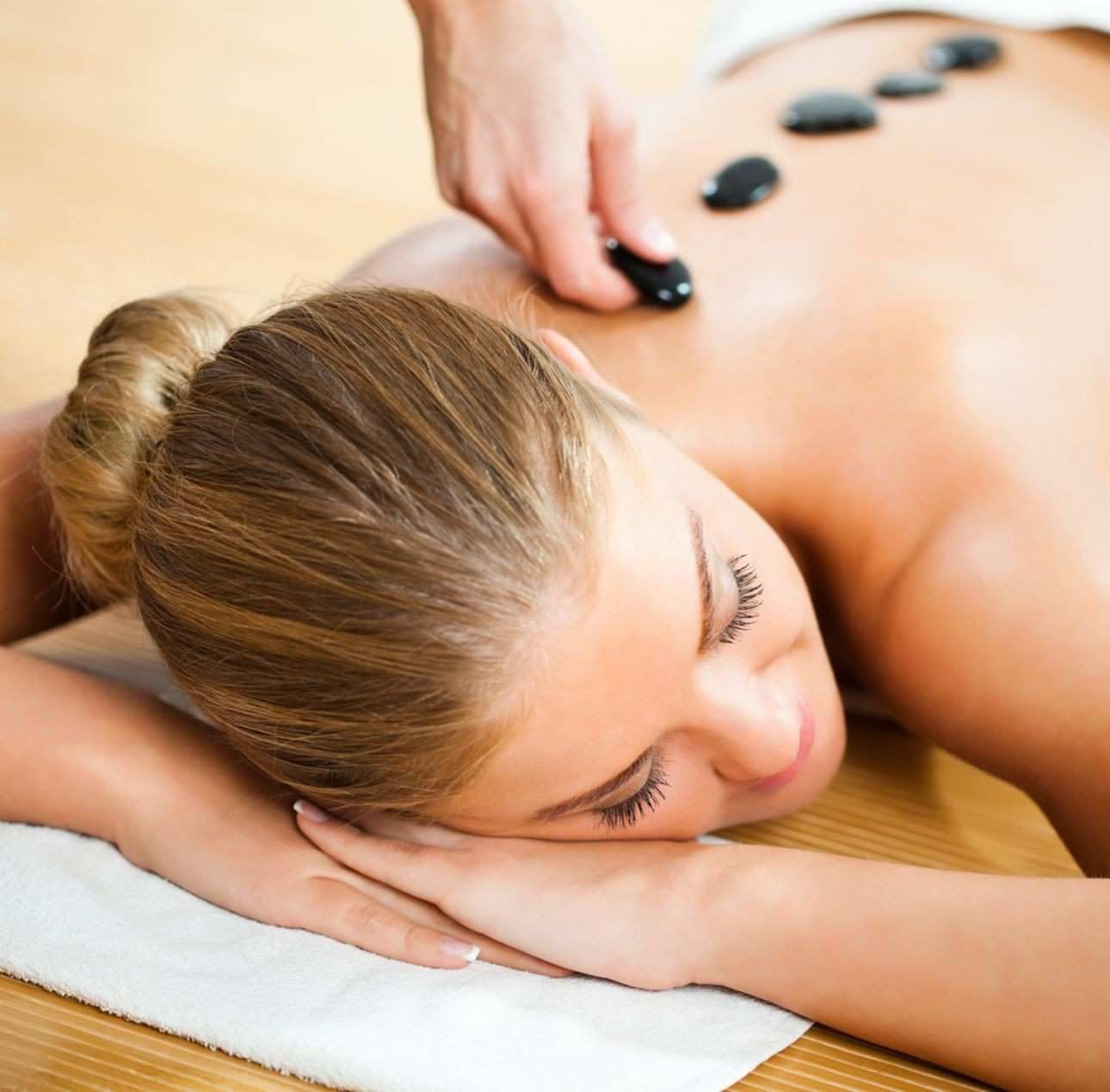 Una persona recibe un relajante masaje facial profesional en un ambiente de spa sereno y con iluminación tenue.