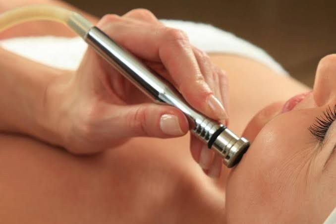 En un spa, un profesional aplica una mascarilla facial sobre la piel de una persona utilizando un pincel.