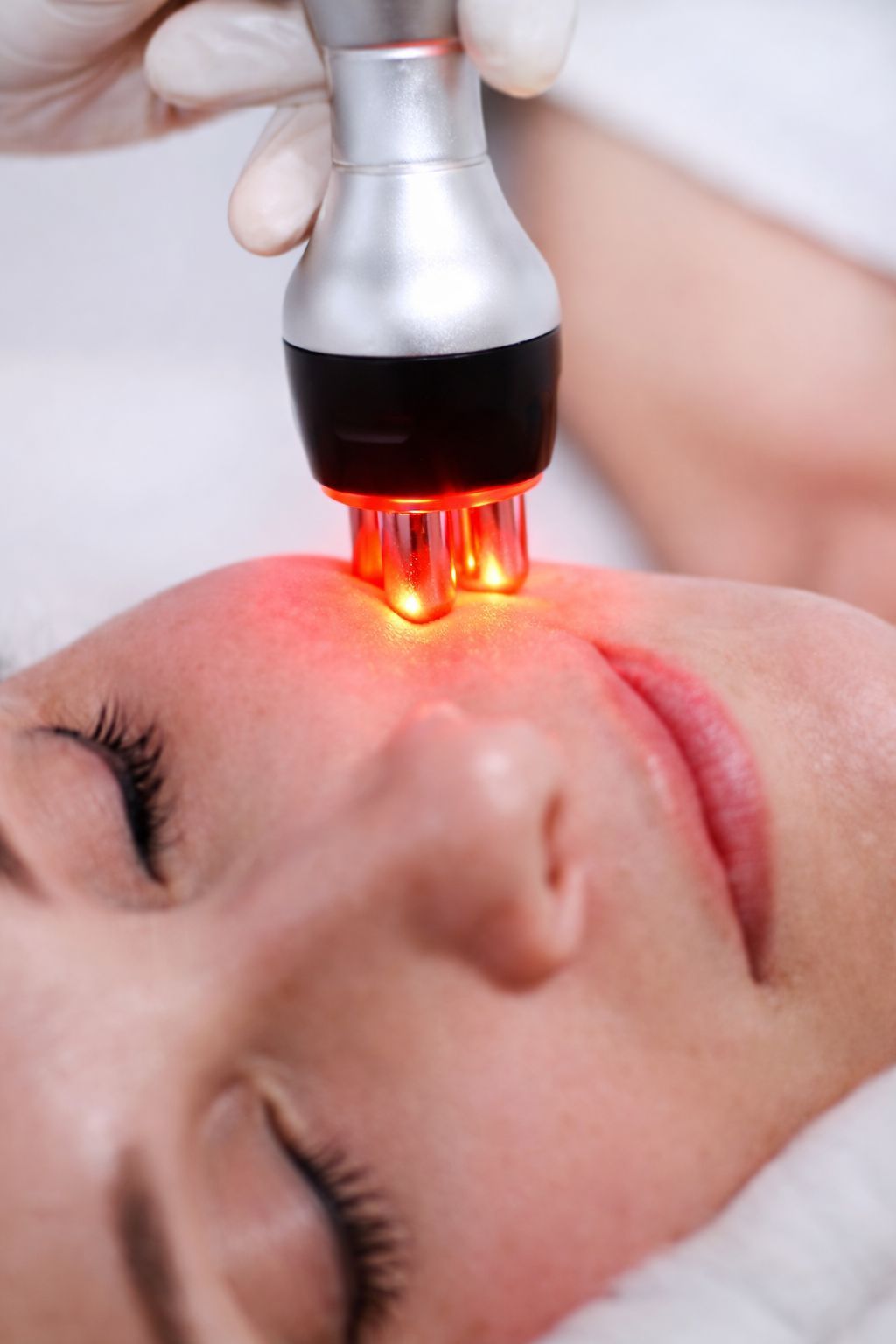 Una persona recibe un relajante masaje facial profesional en un ambiente de spa sereno y con iluminación tenue.