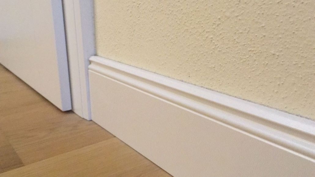 Eine Nahaufnahme einer weißen Fußleiste an einer Wand neben einer Tür.