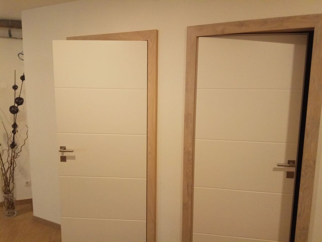 Zwei weiße Türen mit Holzverkleidung in einem Flur