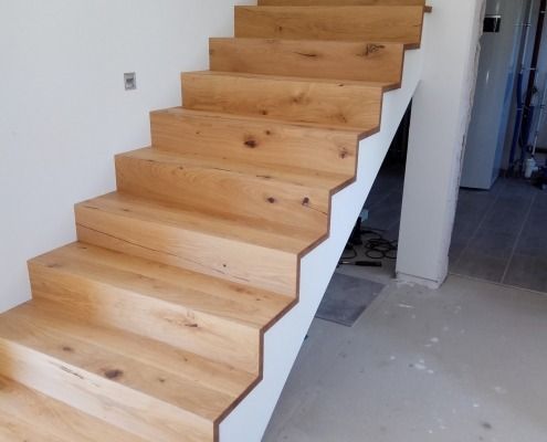 Eine Holztreppe mit einem weißen Geländer in einem Raum.