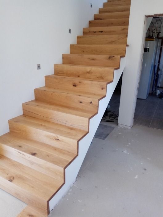 Eine Holztreppe mit einem weißen Geländer in einem Raum