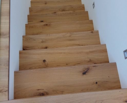 Eine Reihe Holztreppen führen zu einer weißen Wand hinauf.