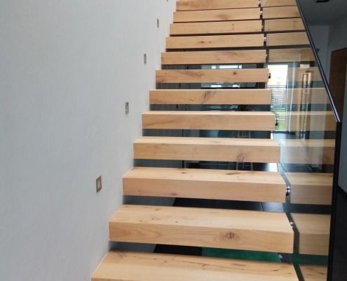 Eine Holztreppe mit einem Glasgeländer in einem Haus