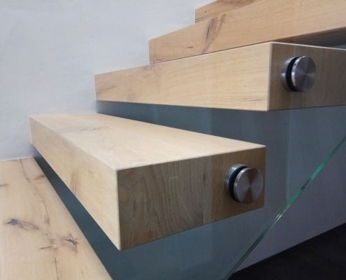 Eine Nahaufnahme einer Holztreppe mit einem Glasgeländer