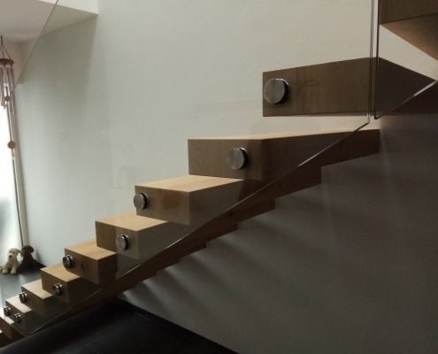 Eine Holztreppe mit einem Glasgeländer in einem Raum