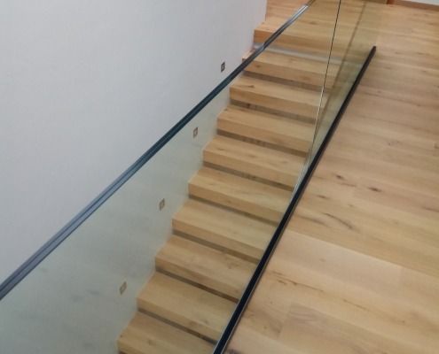Eine Holztreppe mit einem Geländer aus klarem Glas