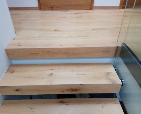 Eine Nahaufnahme einer Holztreppe mit einem Glasgeländer