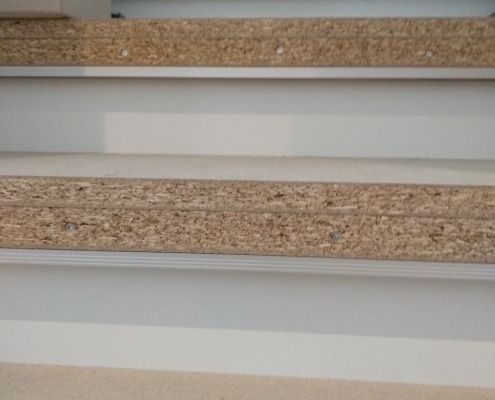 Eine Nahaufnahme einer Holztreppe mit einem weißen Geländer.