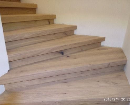 Eine Holztreppe mit Holzboden und weißer Wand.