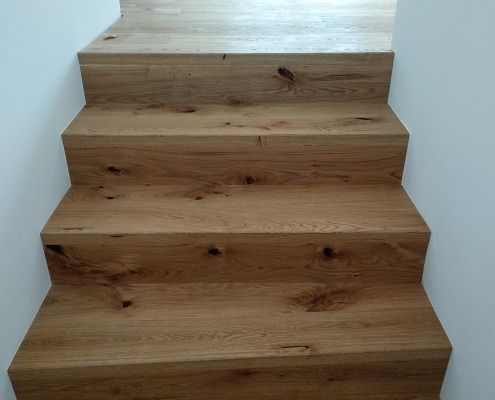 Eine Reihe Holztreppen führen zu einer weißen Wand hinauf.