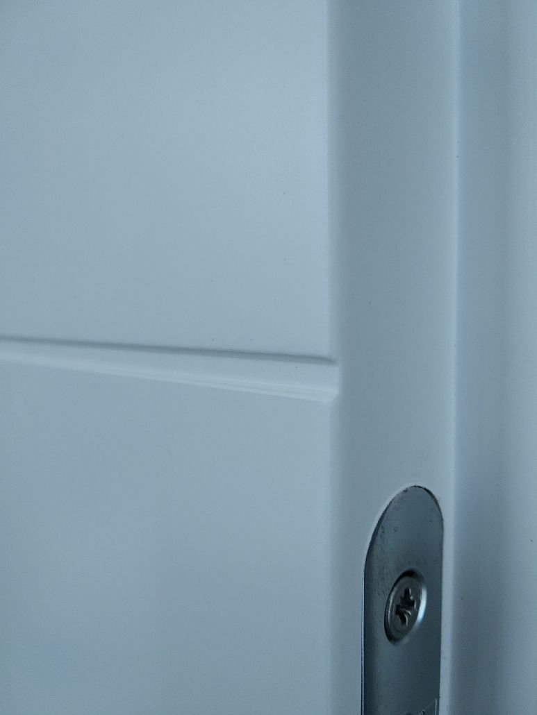 Eine Nahaufnahme einer weißen Tür mit einer Schraube daran.