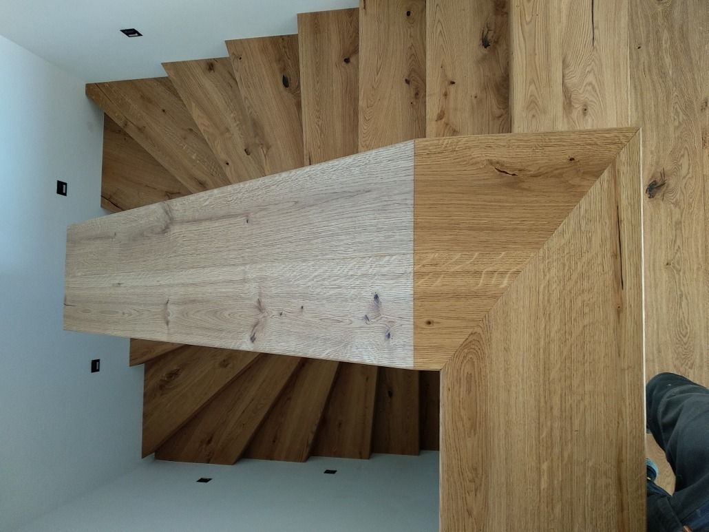 Eine Person steht auf einer Holztreppe in einem Raum.