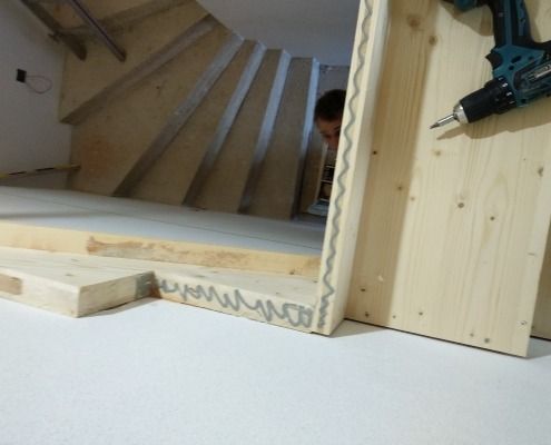 Eine Bohrmaschine liegt auf einem Stück Holz neben einer Treppe