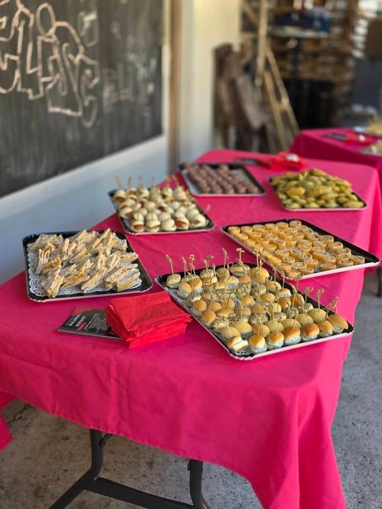 Table dressée avec des plateaux d'amuse-gueules sur une nappe rose.