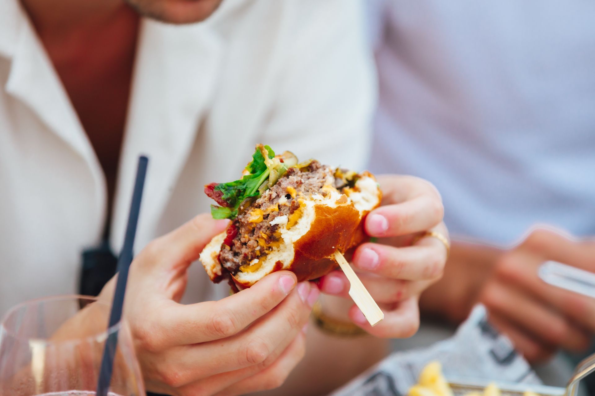 Gros plan sur une personne tenant un hamburger à moitié mangé.