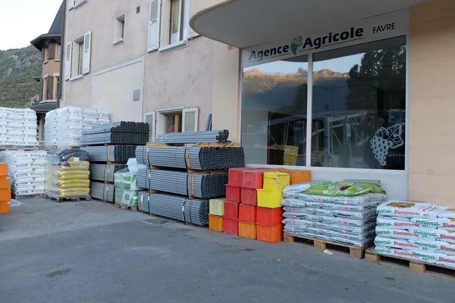 Des piles de marchandises emballées devant la façade de l'Agence Agricole Christian Favre.