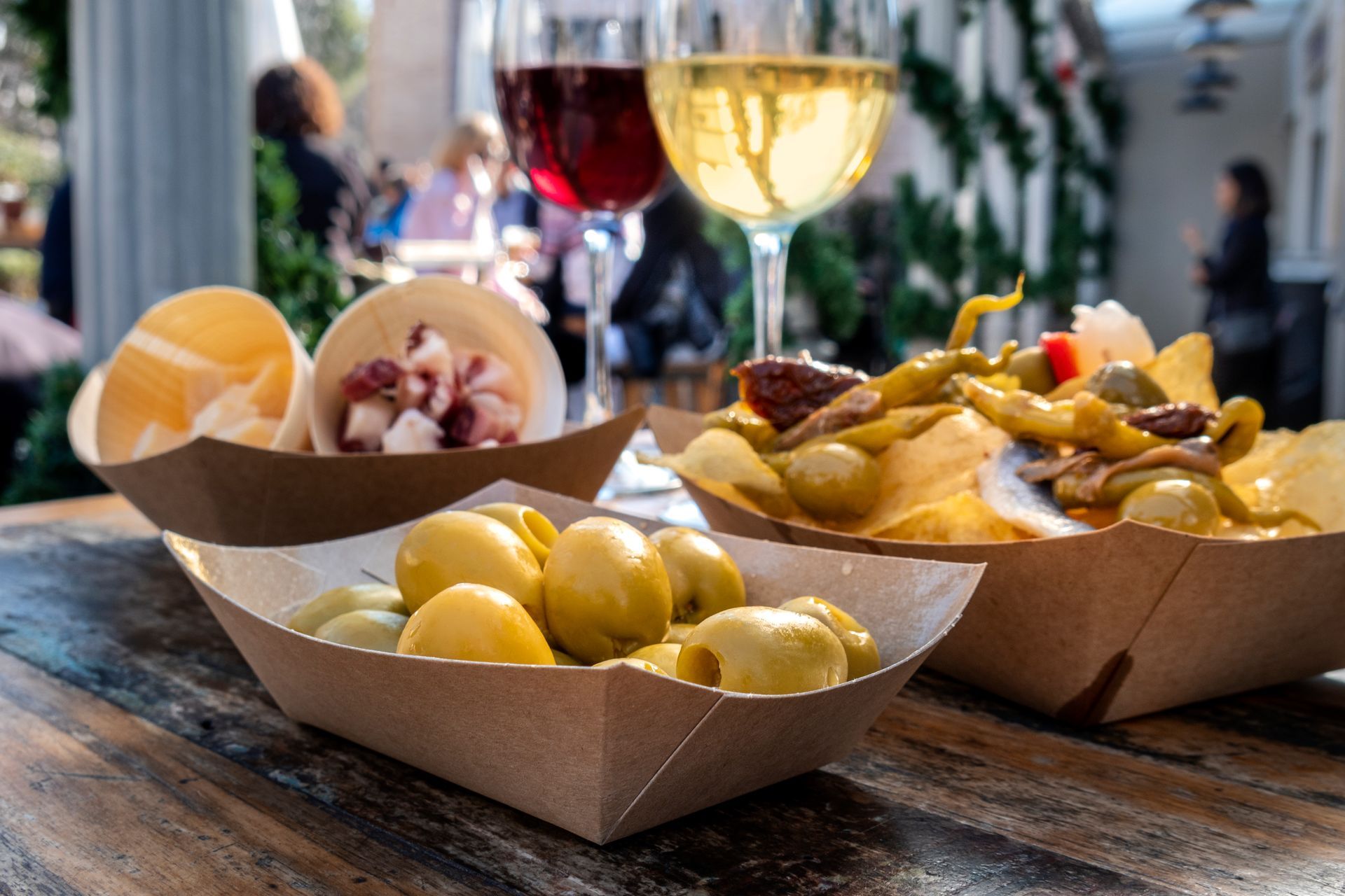 Una mesa de madera cubierta con platos de comida y una copa de vino.