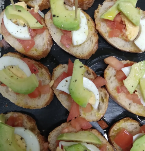 Un montón de aperitivos con aguacate, huevos y tomates.