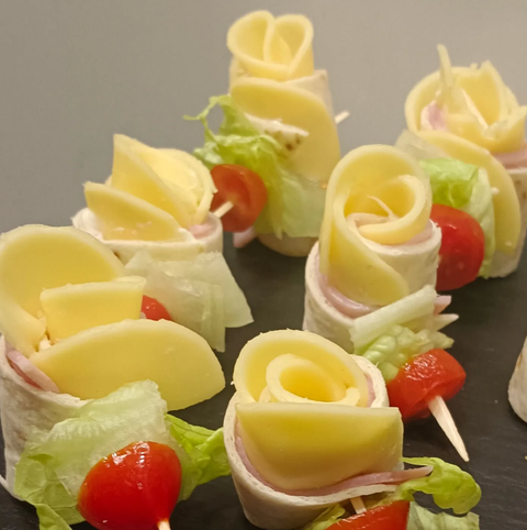 Un montón de rollitos de queso con lechuga y tomates.