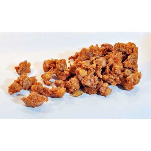 Una pila de carne frita reposa sobre una superficie blanca.