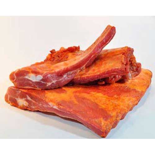 Una pila de costillas de cerdo ahumadas sobre una superficie blanca.