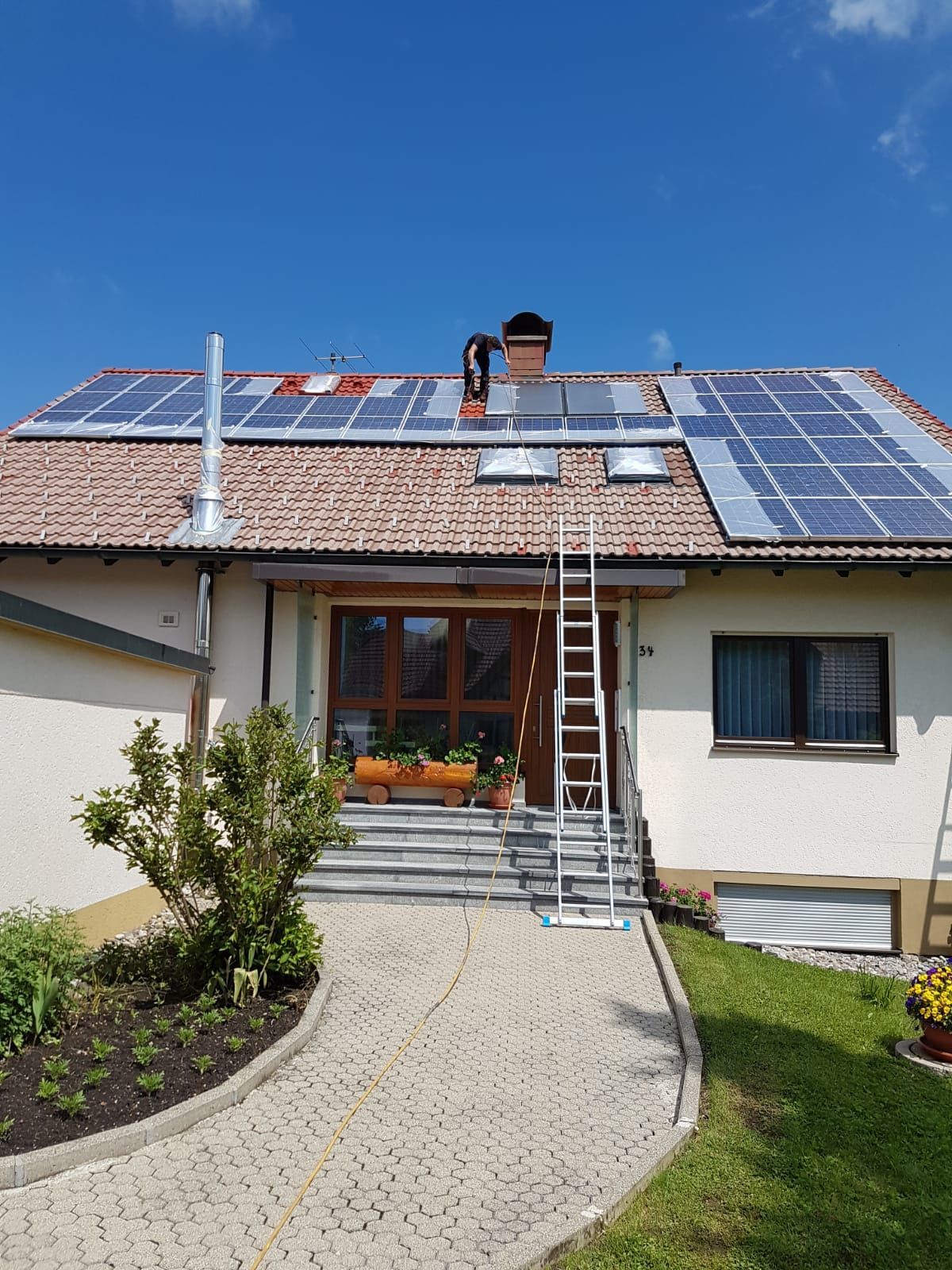 Ein Haus mit Solarzellen auf dem Dach und einer Leiter davor