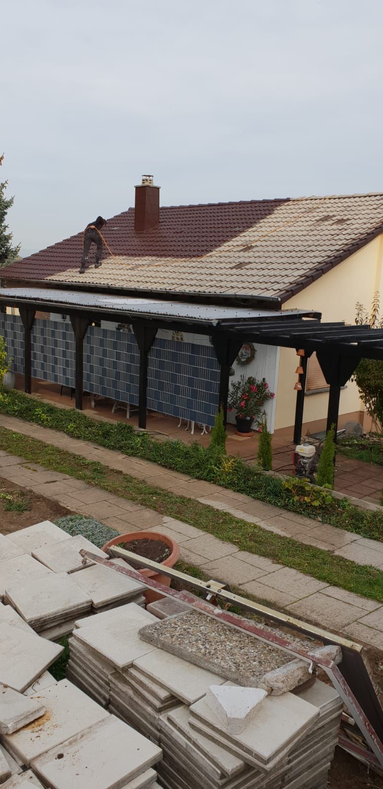 Ein Haus mit einer Pergola und vielen Pflastersteinen auf dem Boden davor