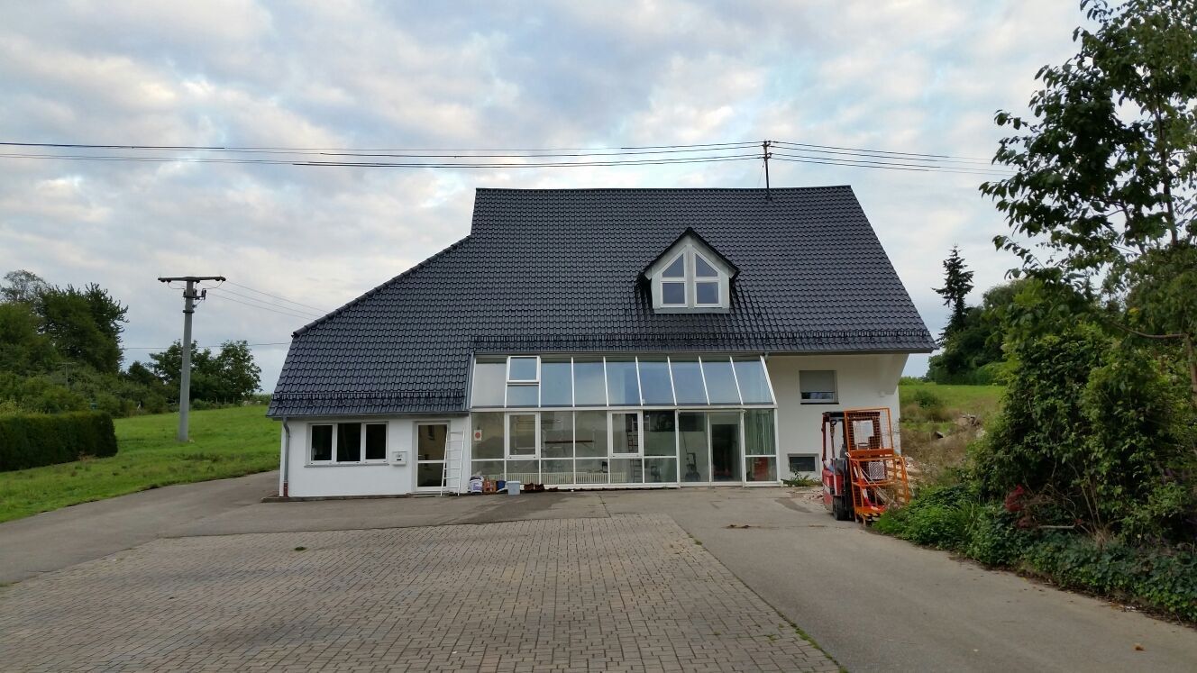 Ein weißes Haus mit schwarzem Dach und Wintergarten