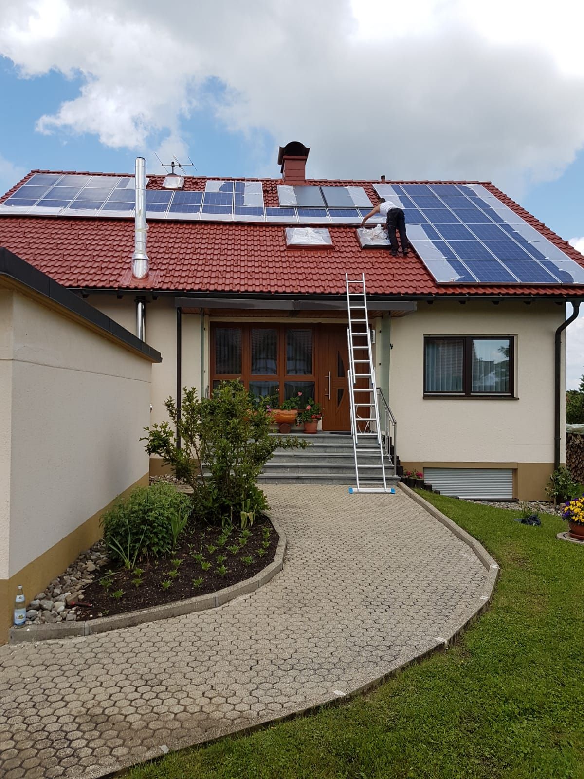 Ein Haus mit Solarzellen auf dem Dach und einer Leiter davor