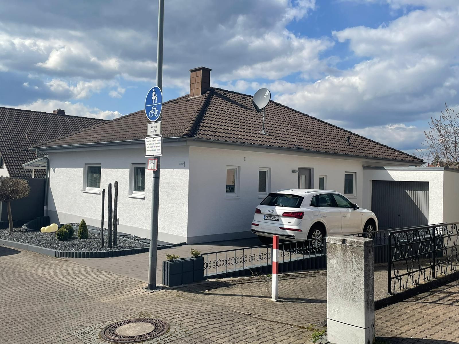 Ein weißes Auto parkt vor einem weißen Haus