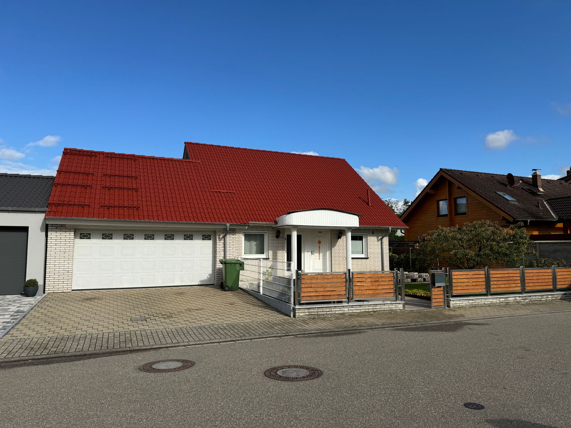 Ein Haus mit einem roten Dach und einem weißen Garagentor