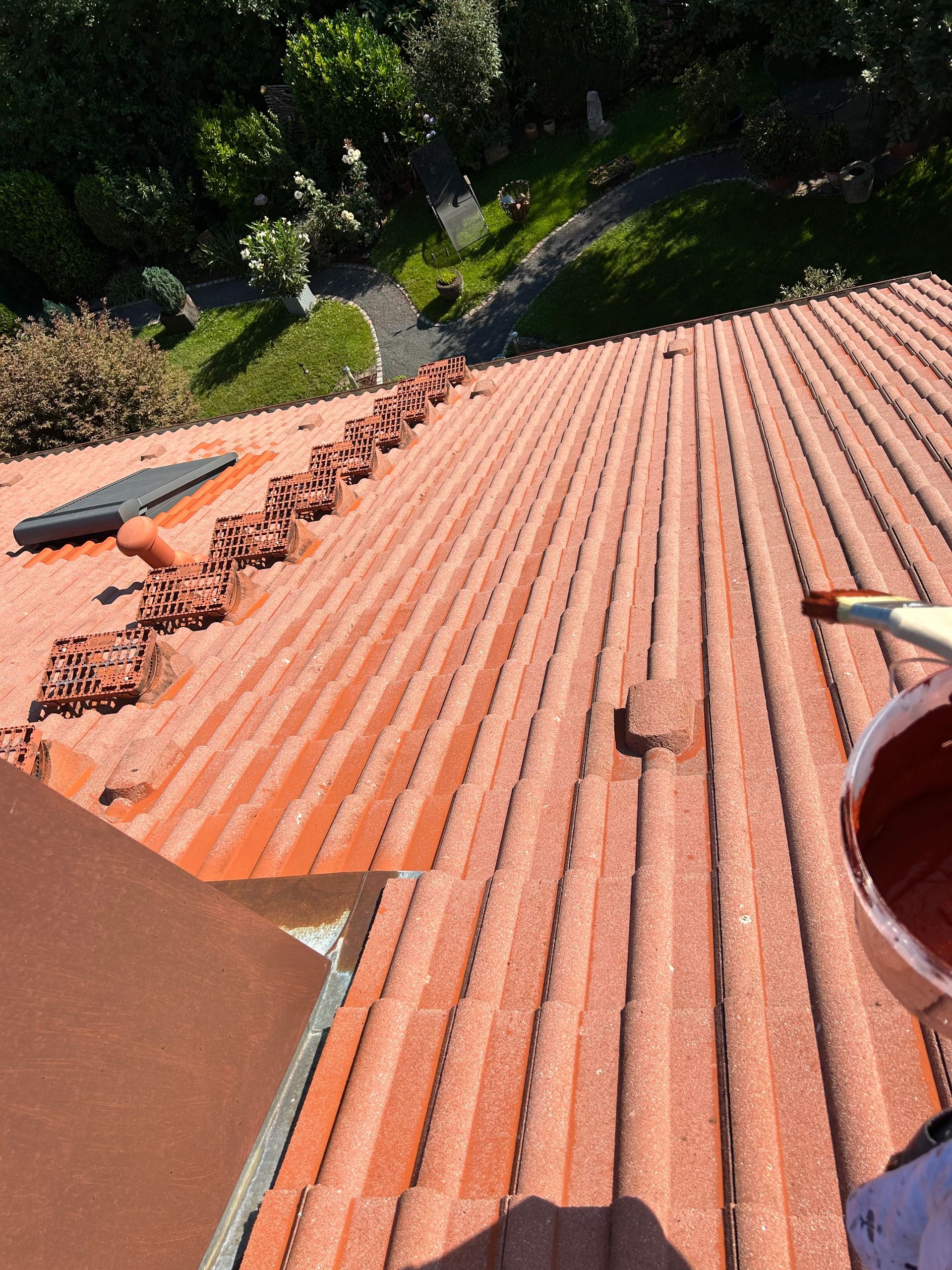 Eine Person streicht ein Dach mit einem Pinsel