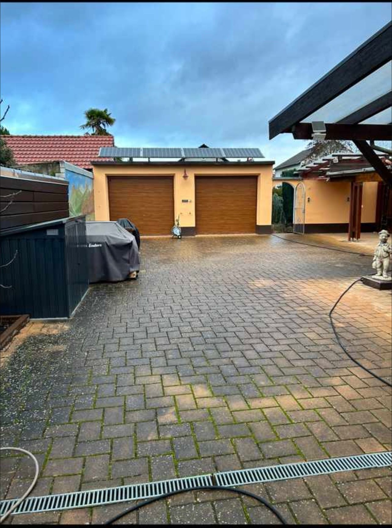 Eine gemauerte Auffahrt, die zu einer Garage mit zwei Garagentoren führt