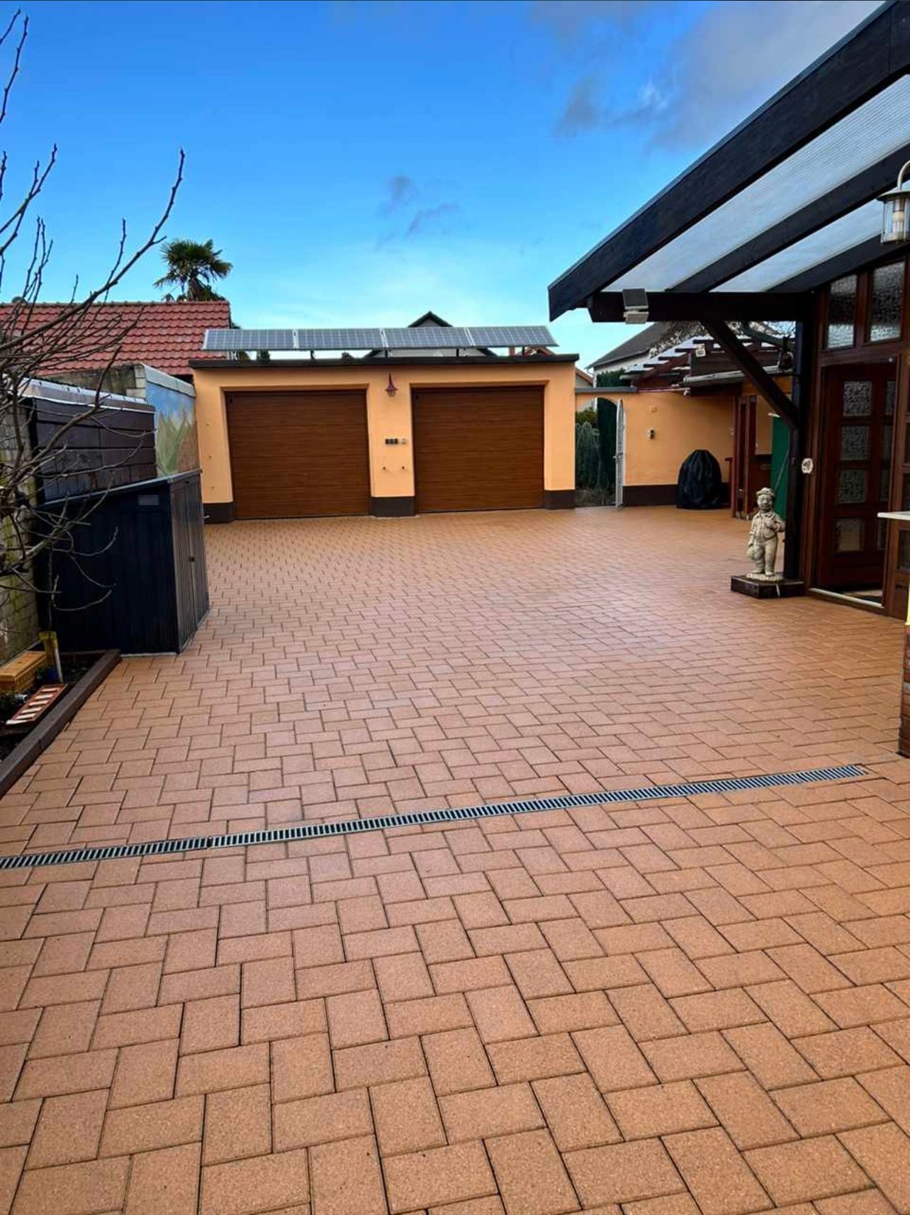 Eine gemauerte Auffahrt, die zu einer Garage mit zwei Garagentoren führt