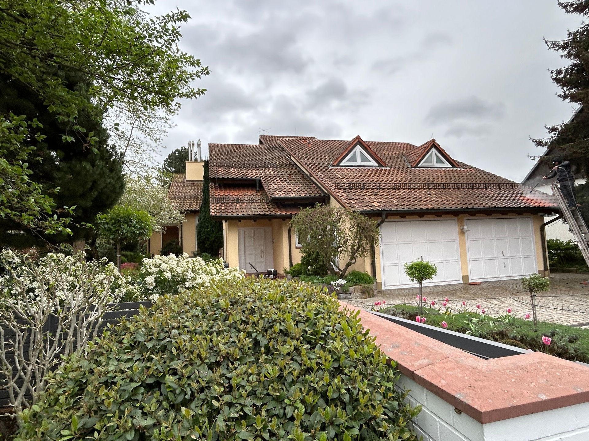 Ein großes Haus mit einem Ziegeldach ist von Bäumen und Büschen umgeben