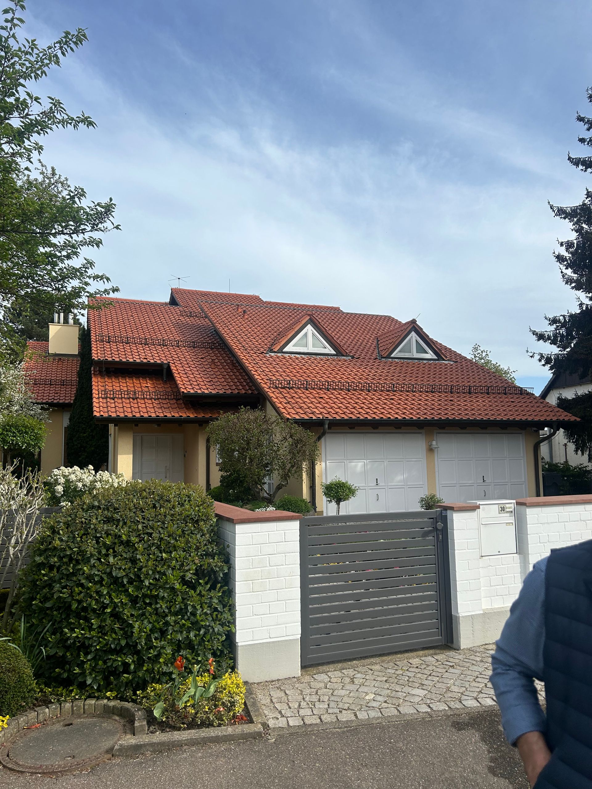 Ein Mann steht vor einem Haus mit einem roten Ziegeldach