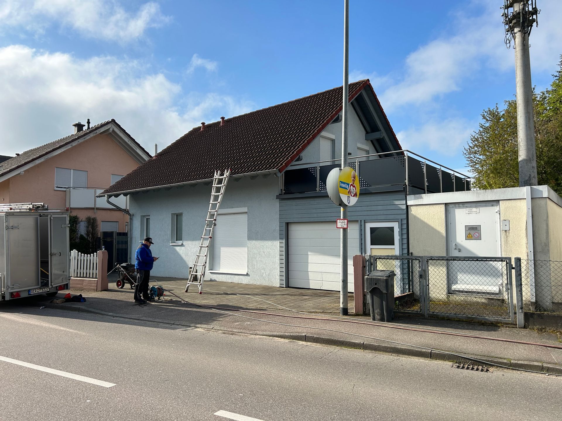 Ein Mann steht vor einem Haus, an dem eine Leiter befestigt ist