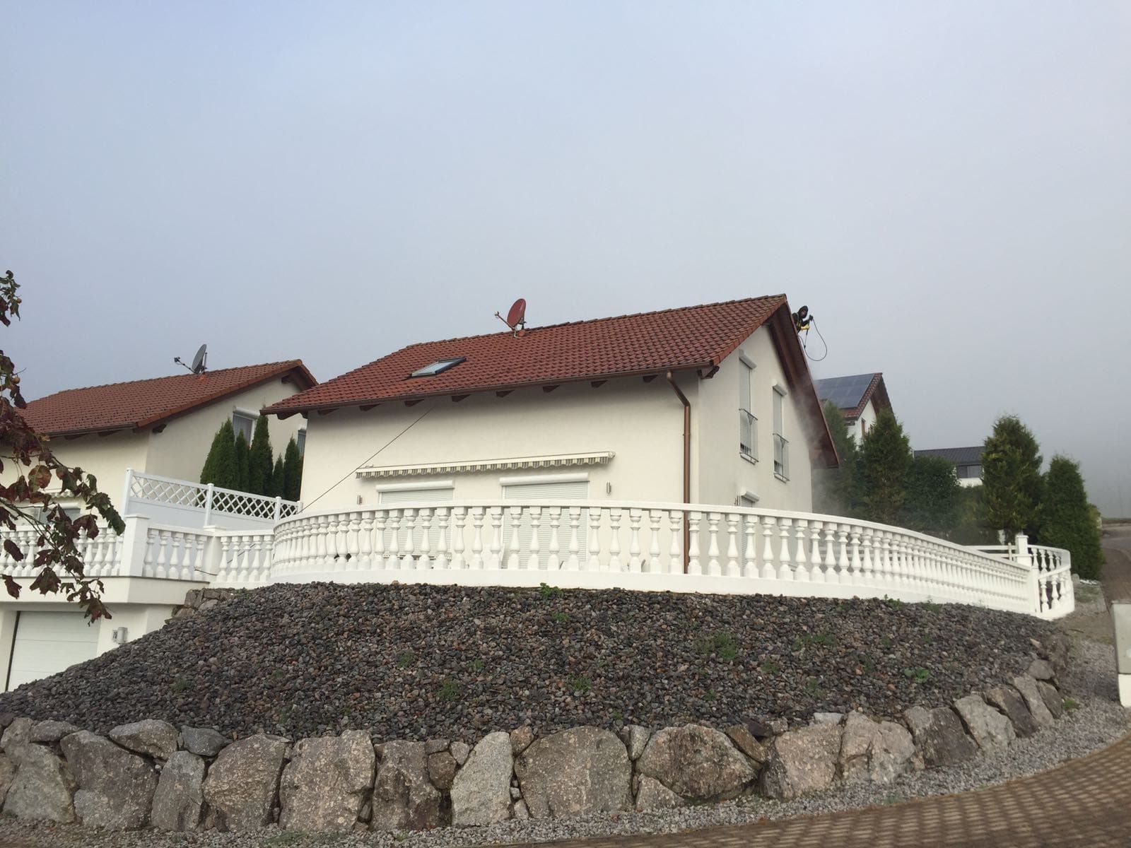 Ein weißes Haus mit einem roten Dach und einem weißen Zaun