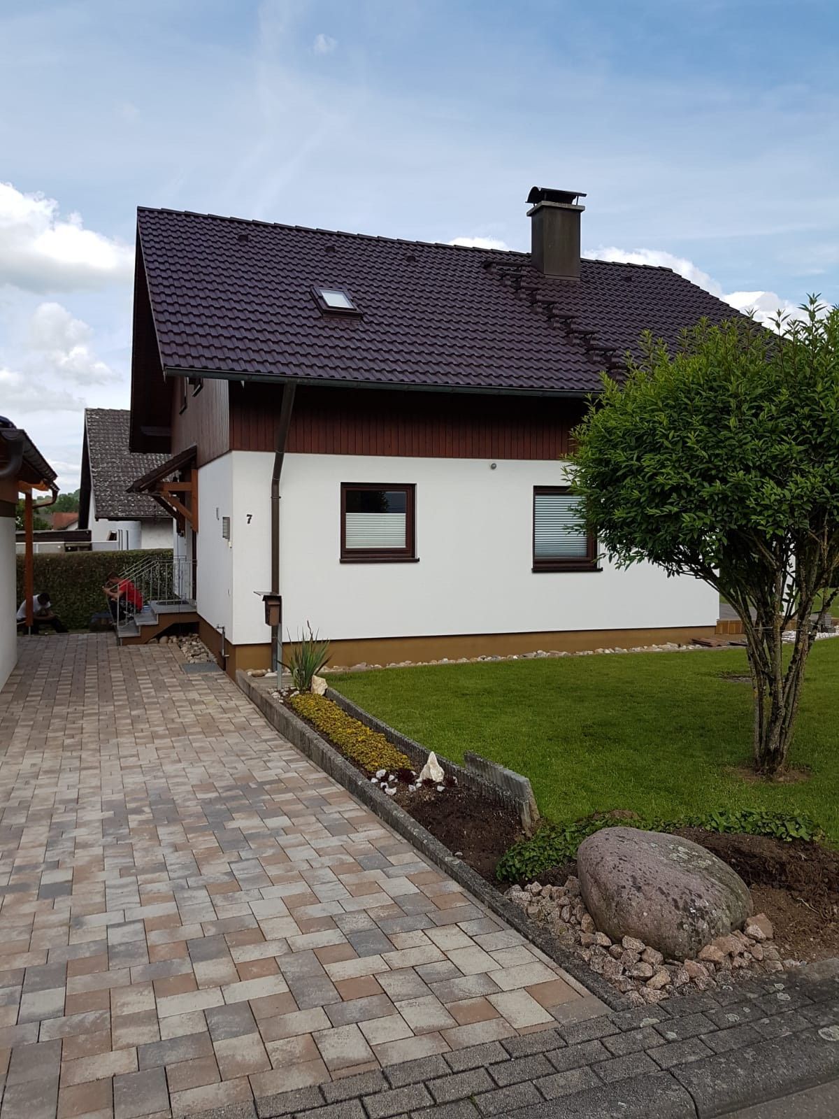 Ein weißes Haus mit schwarzem Dach und einer gepflasterten Auffahrt