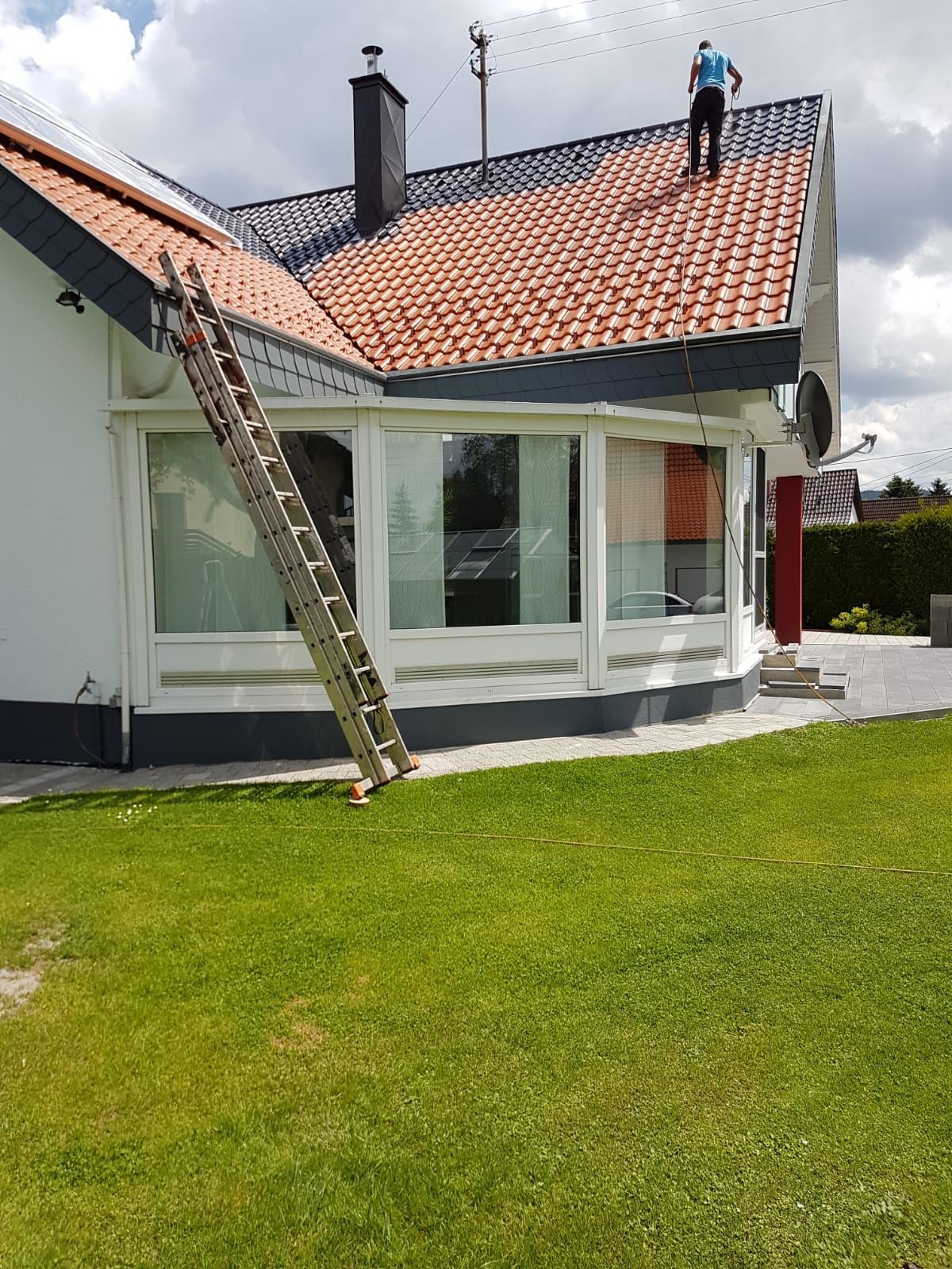 Ein Mann steht auf dem Dach eines Hauses, an dem eine Leiter befestigt ist