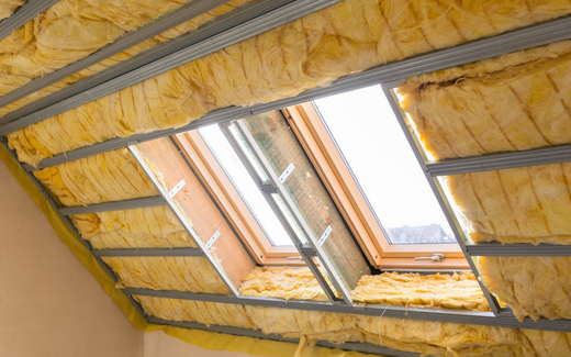Toiture de combles isolée avec deux fenêtres de toit et poutres en bois apparentes