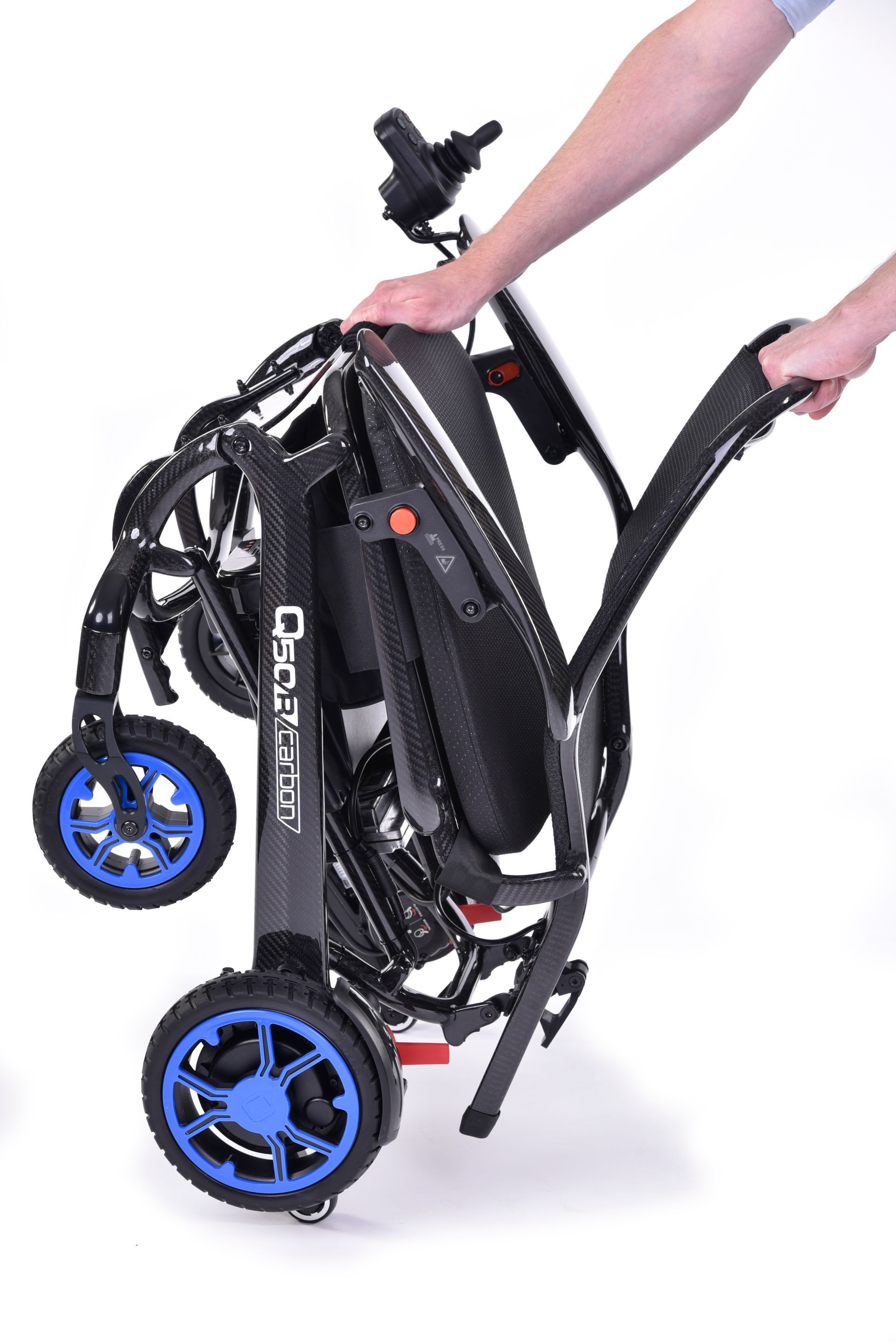Eine Person hält einen zusammengeklappten Elektrorollstuhl mit blauen Rädern.